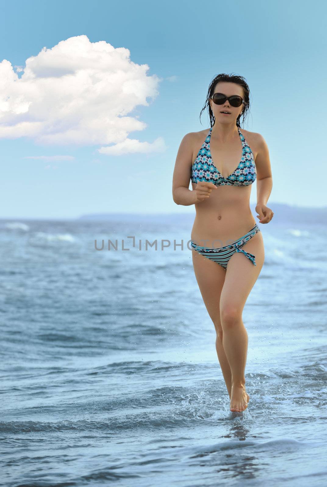 The girl running on seacoast. The European appearance in sunglasses