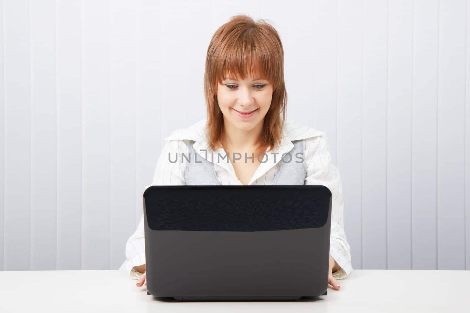 Attractive smiling happy girl with a laptop in the office
