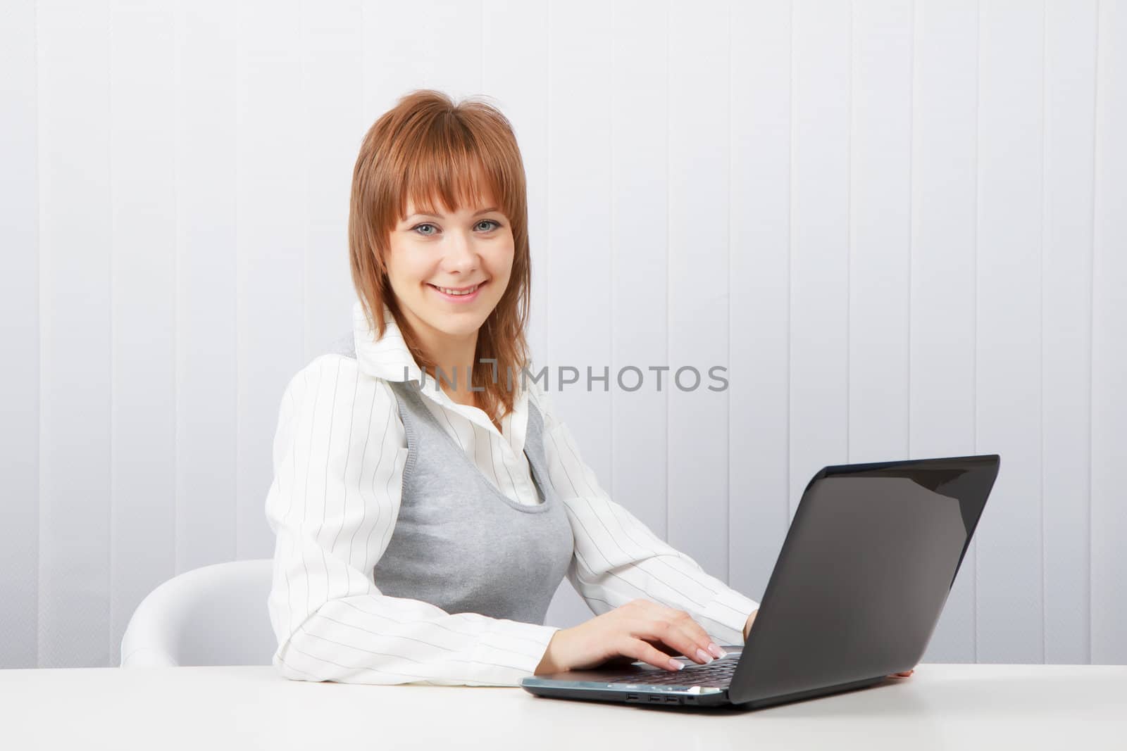 Attractive smiling happy girl with a laptop in the office
