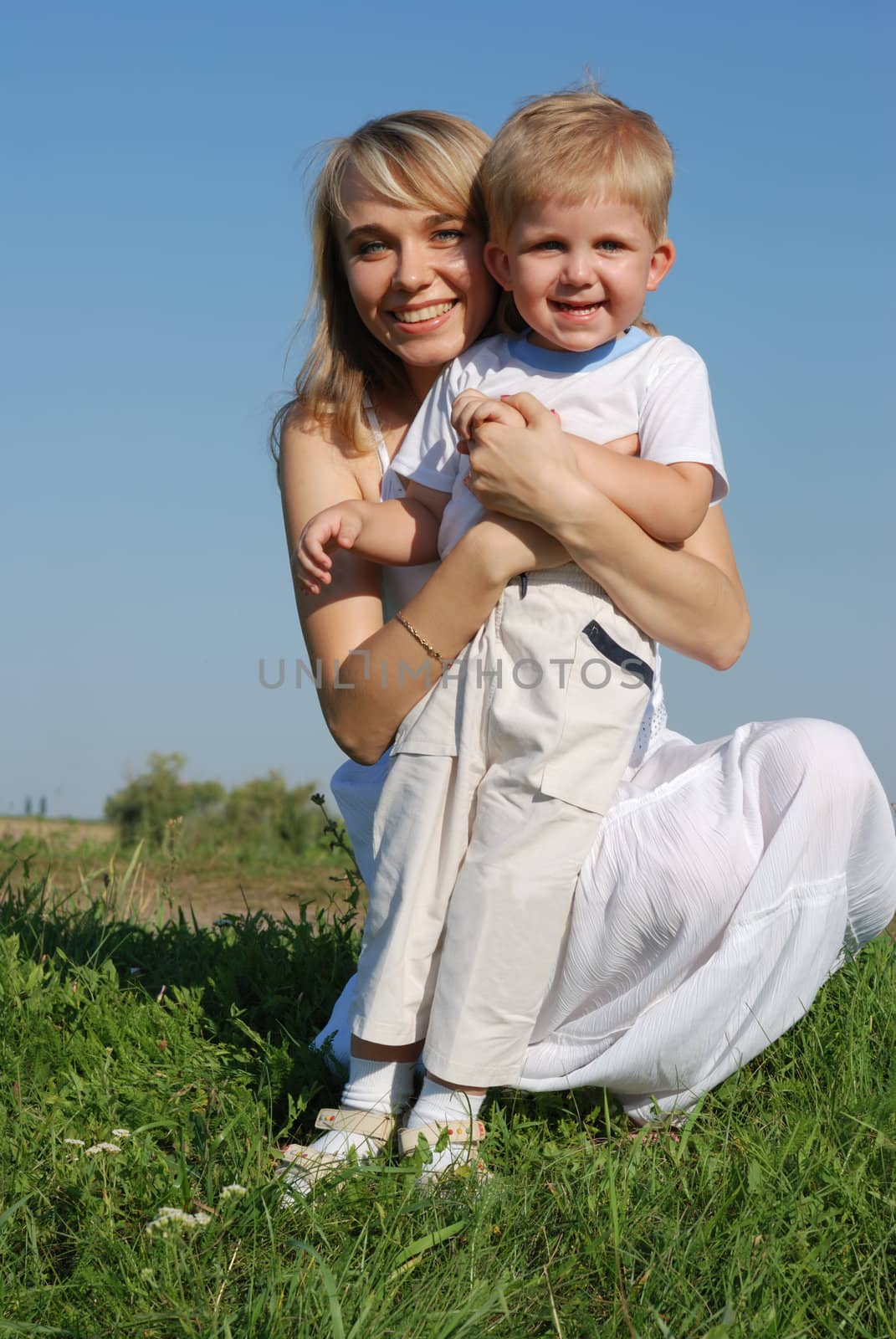 The mother and son. Happy people on a meadow with the clear blue sky