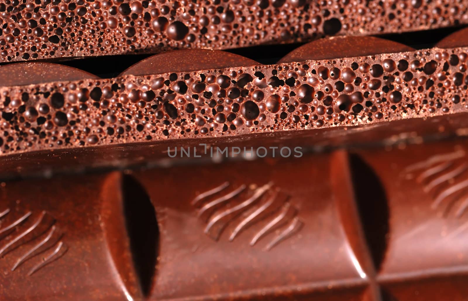 Chocolate. The broken tile of porous black chocolate