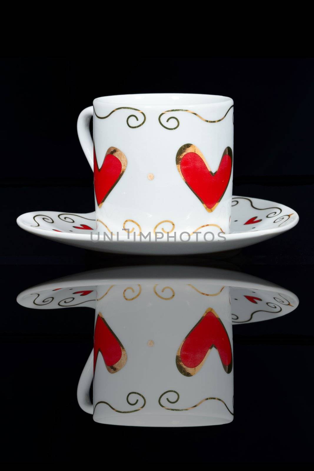 White cup with hearts is a black table, reflected in it.