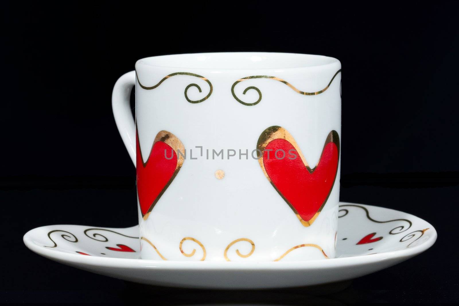 White cup with hearts isolated on black background.