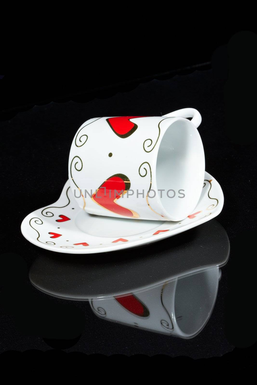 White cup with hearts is a black table, reflected in it.