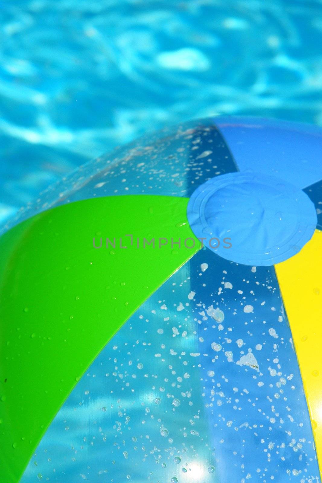 A colorful beach ball floating on the swimming pool.