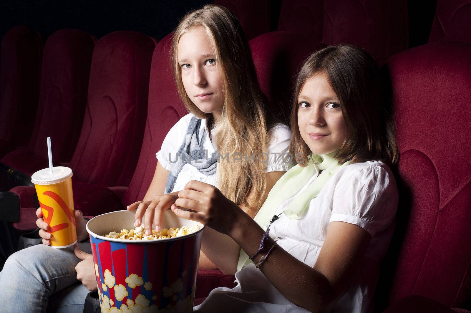 two beautiful girls watching a movie at the cinema by adam121