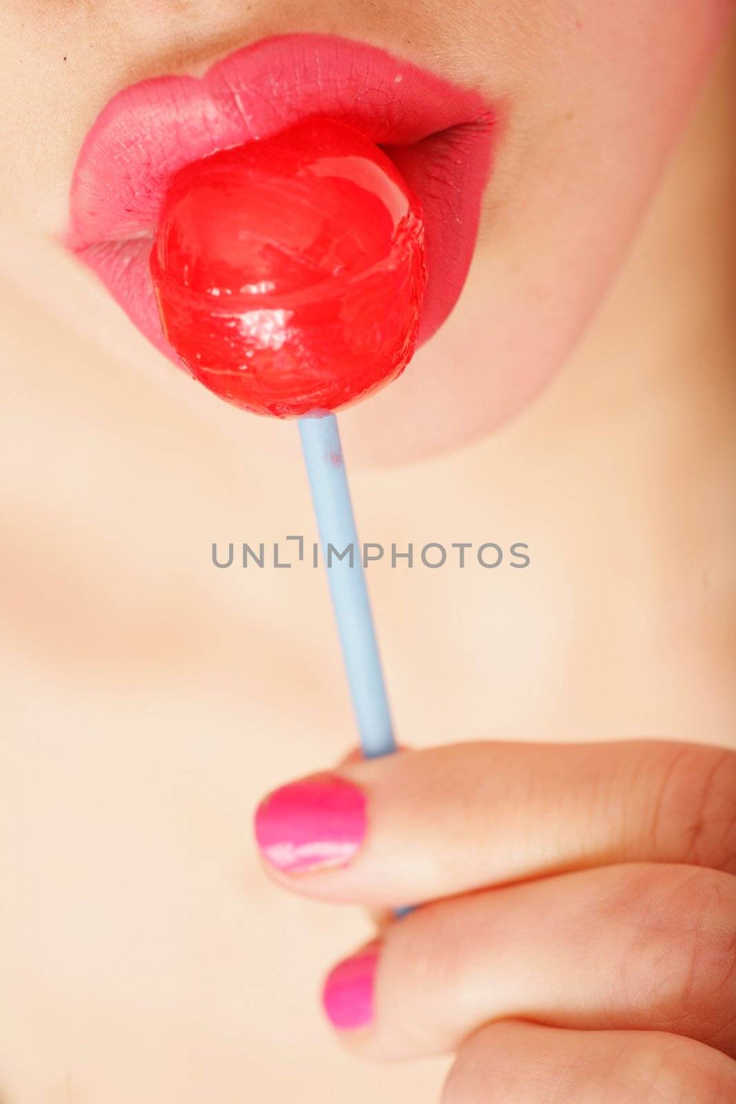 close-up of a red lollipop on pink lips