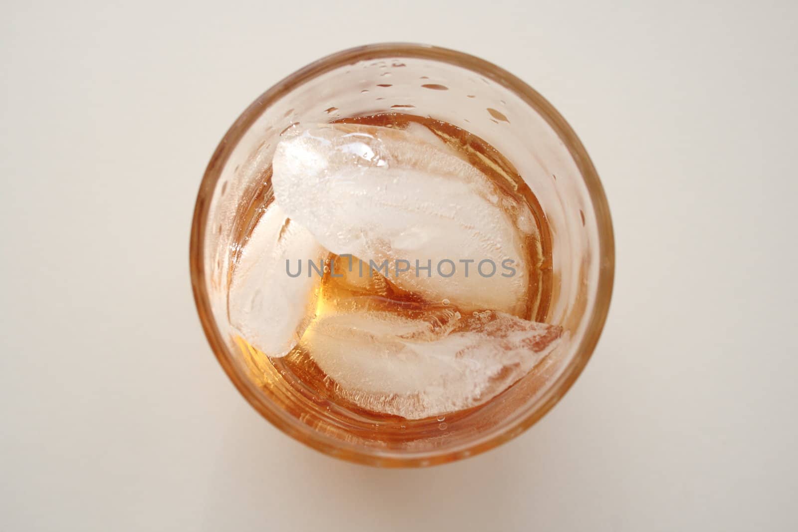 top down view of a glass of alcohol with ice cubes by njene