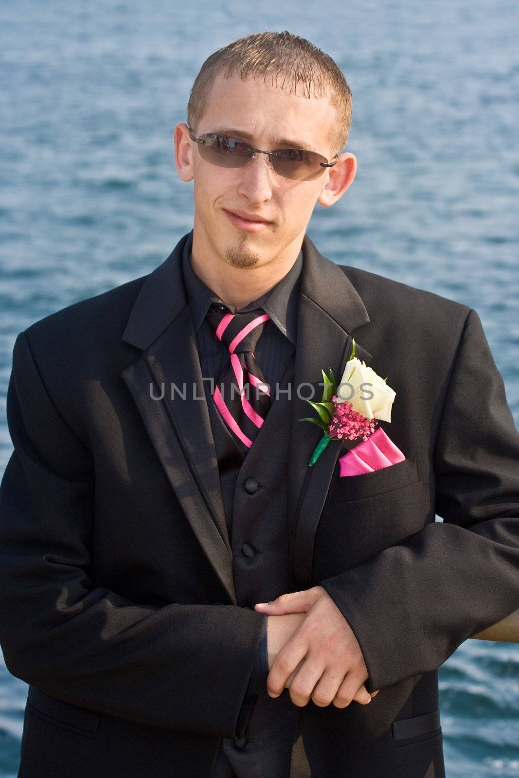 Portrait of a teenage boy in a tuxedo. Background is a blue ocean. The teen is dressed for a high school prom but the photo could be used to represent any formal occasion.