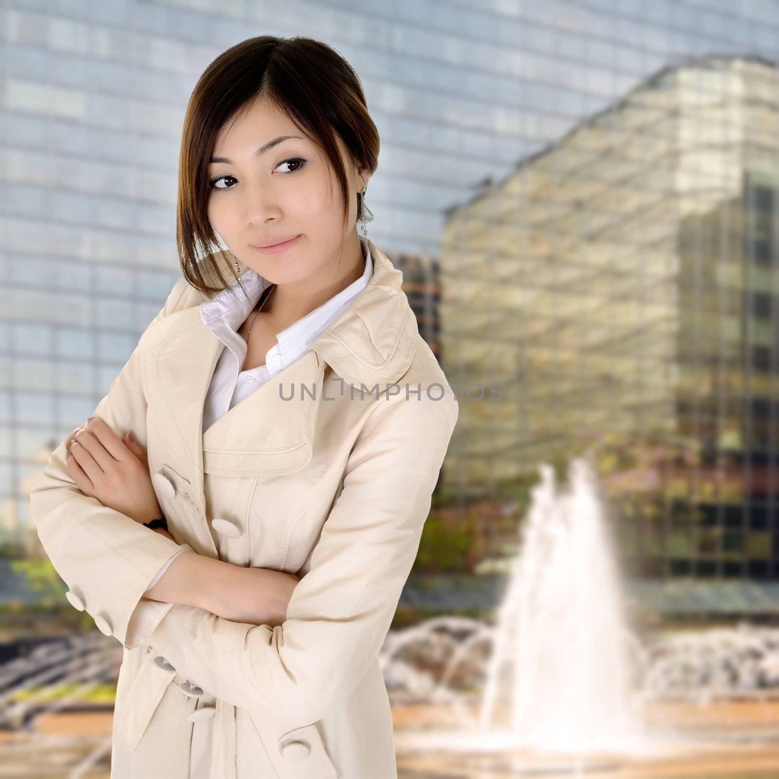 Successful young executive woman of Asian standing with modern building exterior.