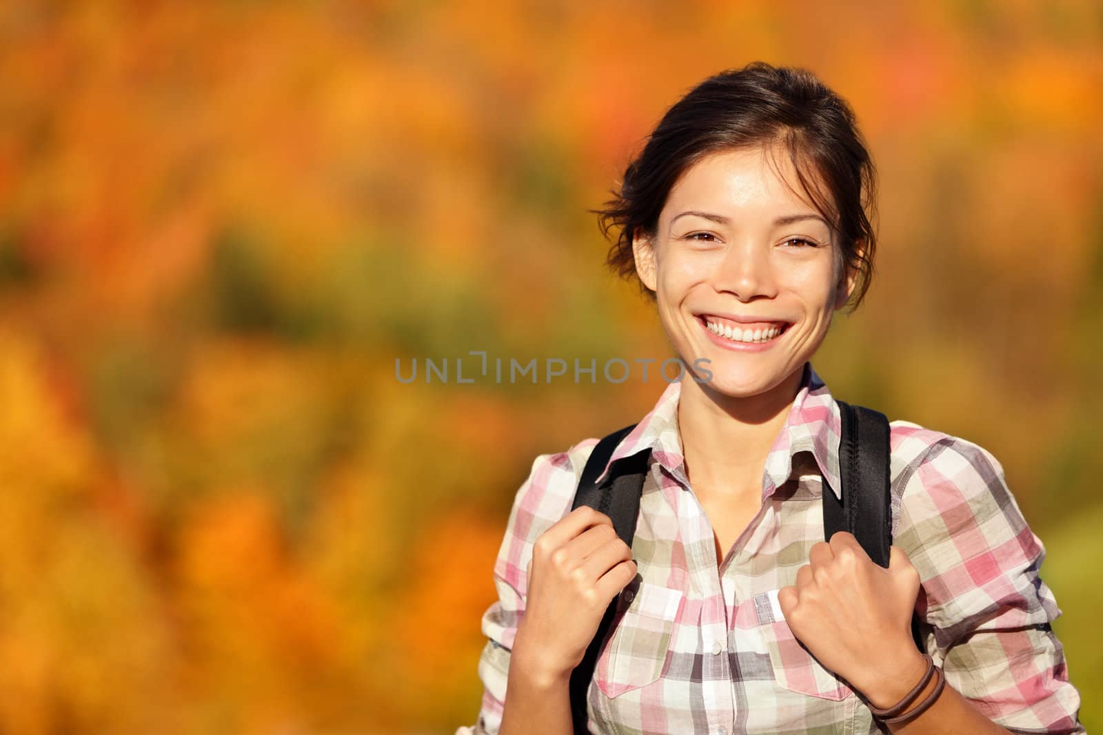 hiker hiking in Autumn forest. Young outdoors woman smiling happy during hike in beautiful fall colored forest. Fresh Mixed race Chinese Asian Caucasian female model.