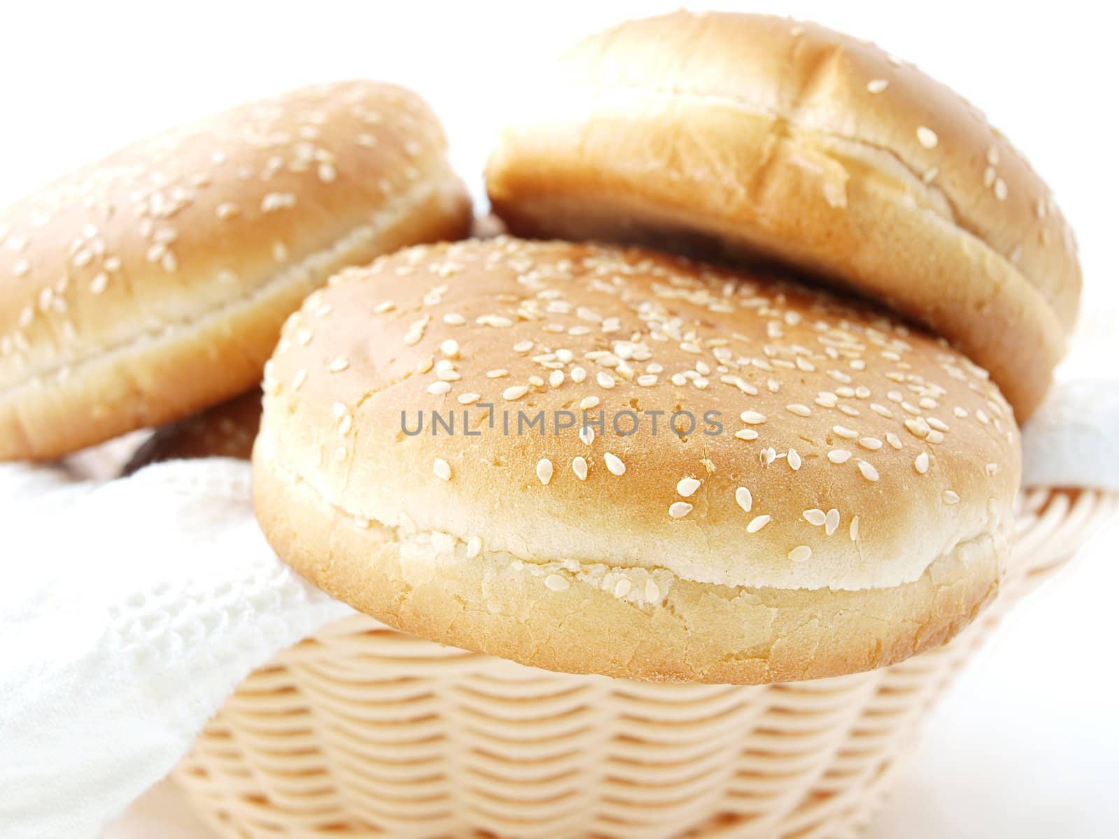 Hamburger buns in wooden basket, with a white towle towards white