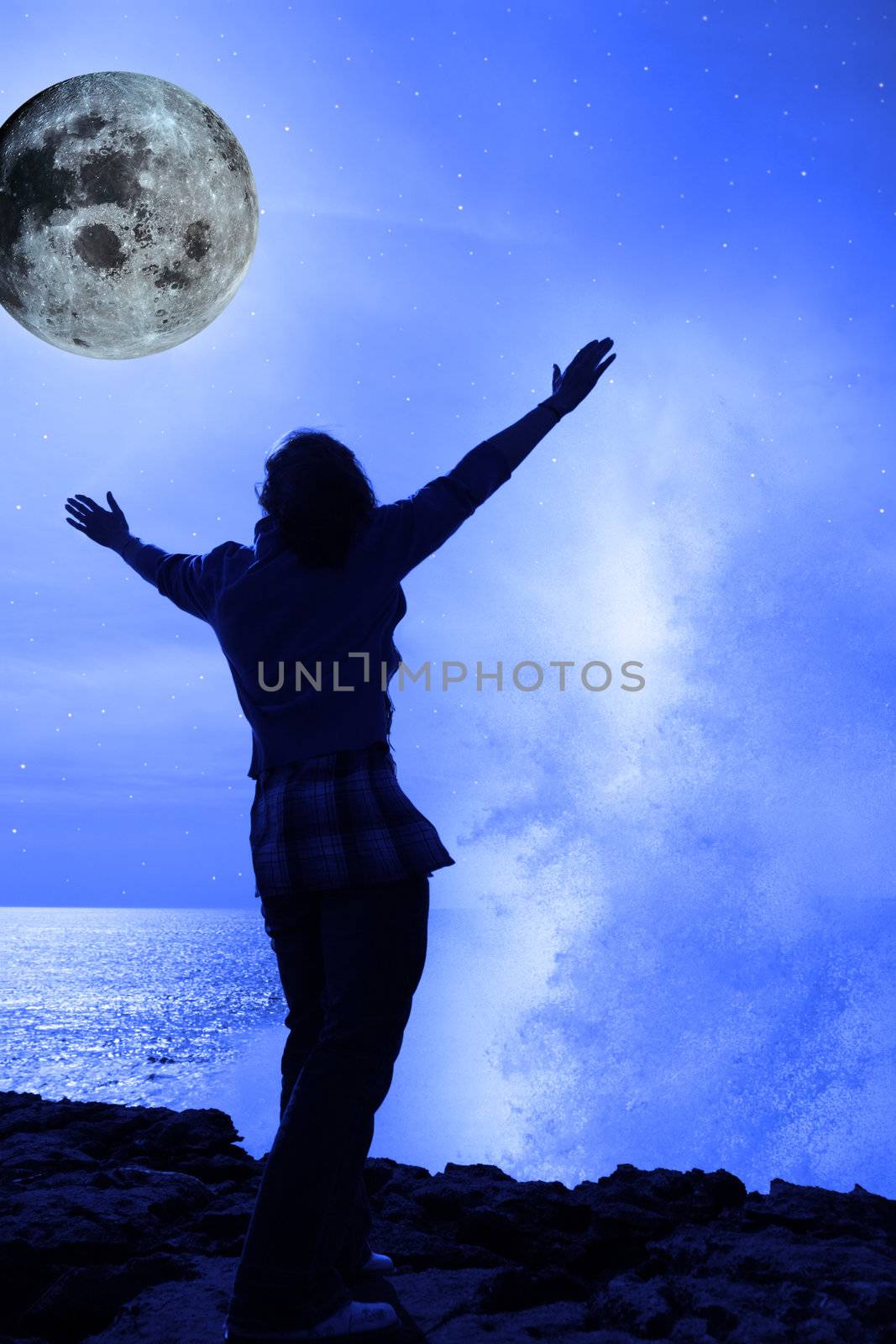 a woman with raised hands facing a wave and full moon on cliff e by morrbyte