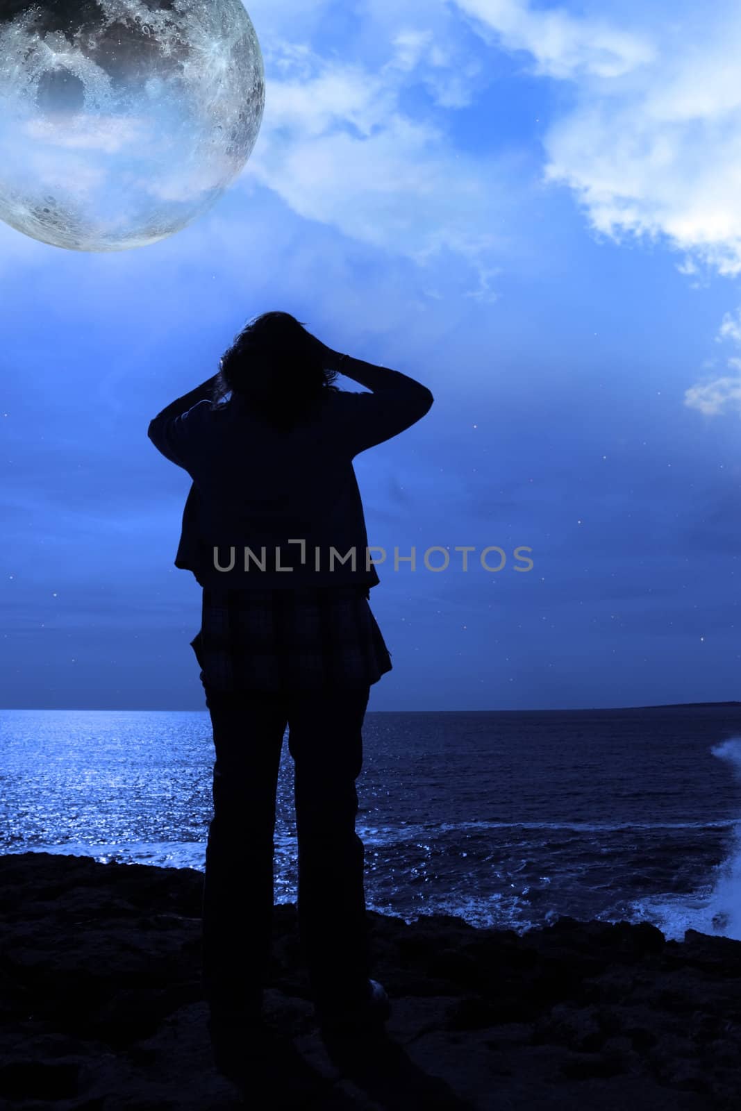 silhouette of a sad lone woman with full moon on a cliff edge by morrbyte