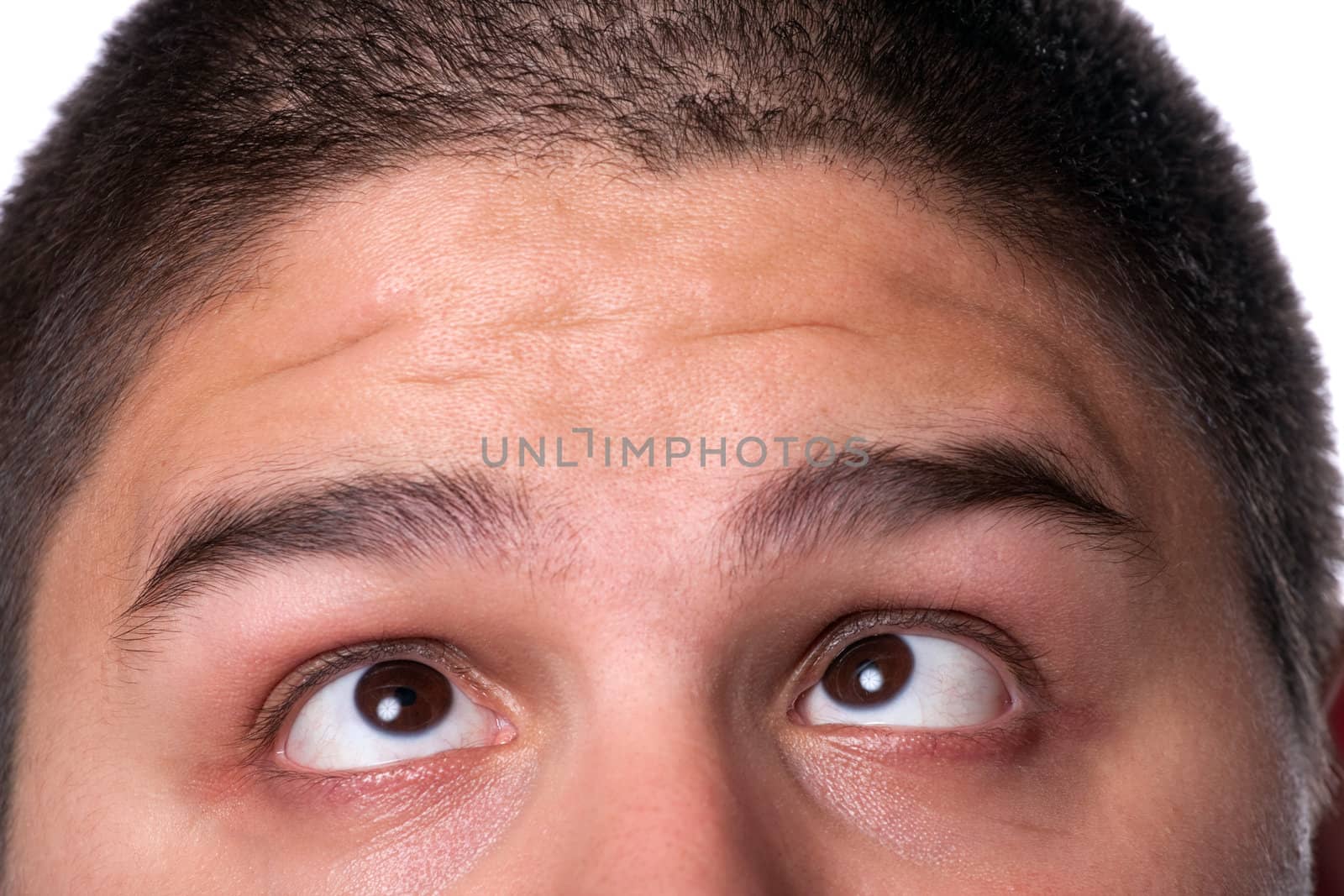 A young man that looks very confused and cross eyed with his eyes looking upward towards his forehead.