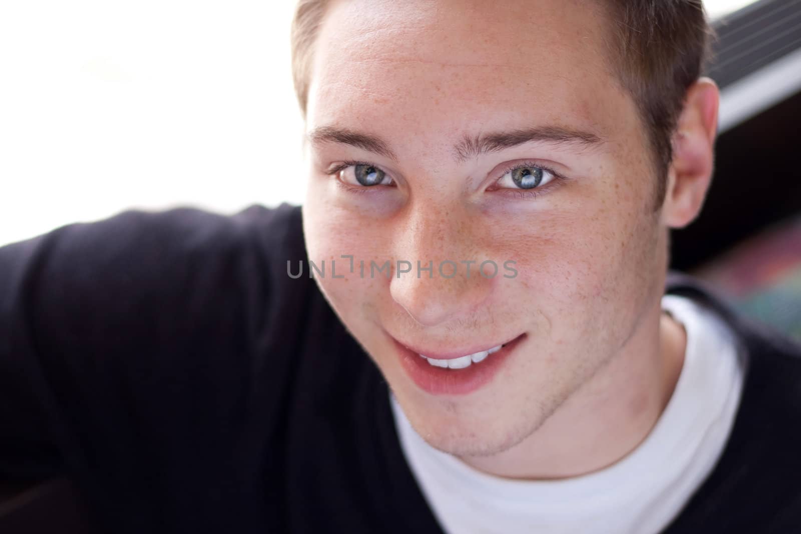Portrait of a smiling young man in his early twenties. Shallow depth of field.