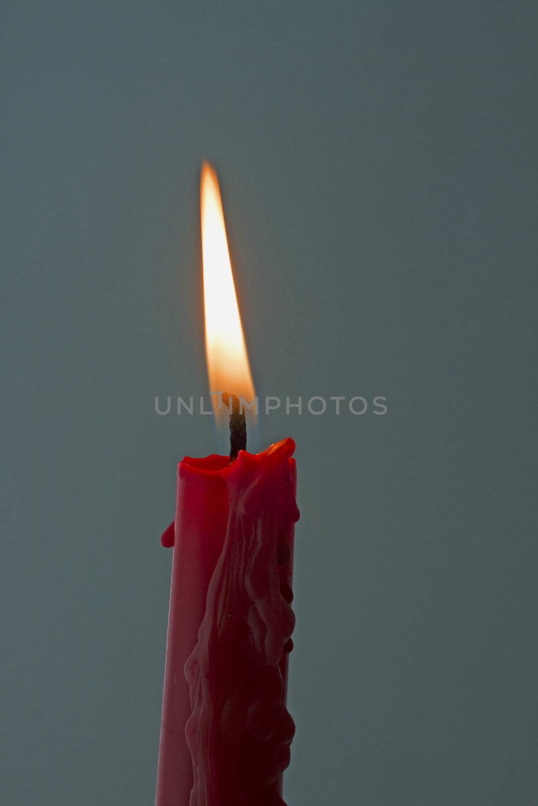 Lite red candle over a dark gray background