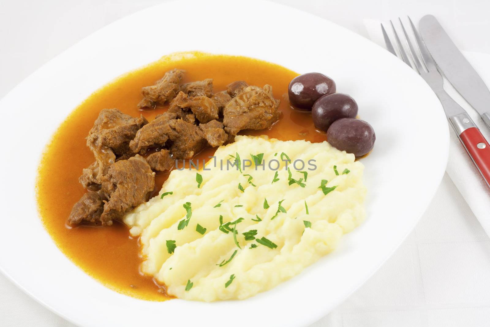 Beef goulash with mashed potato spiced with parsley and three brown olives.