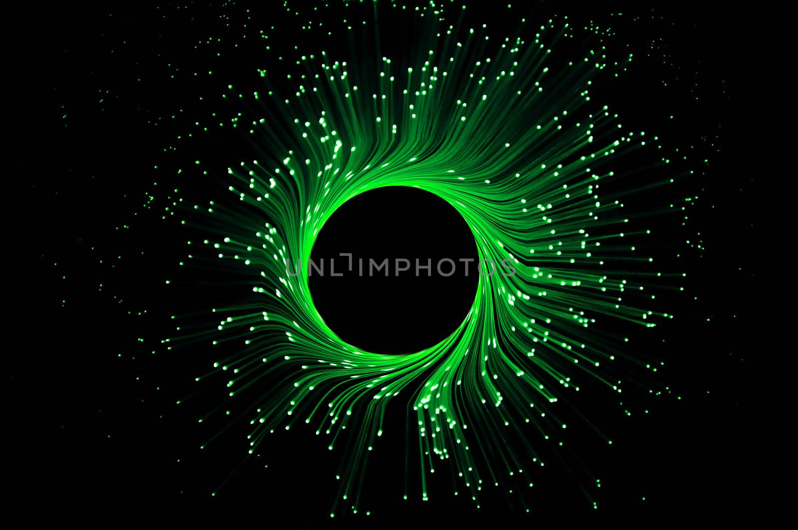 Many illuminated fibre optic light strands forming a ring against black background