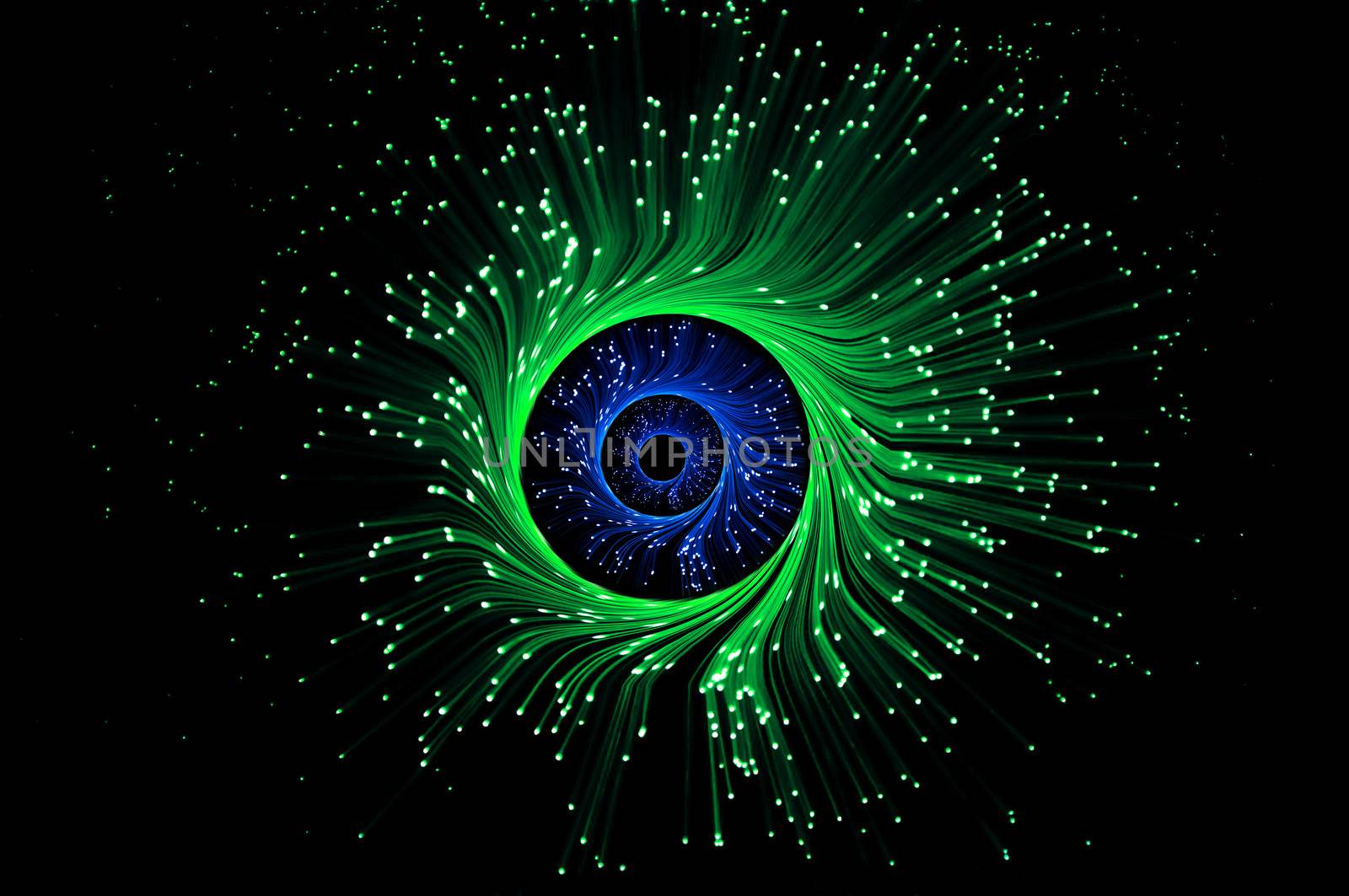 Three rings of illuminated green and blue fiber optic light strands against black background