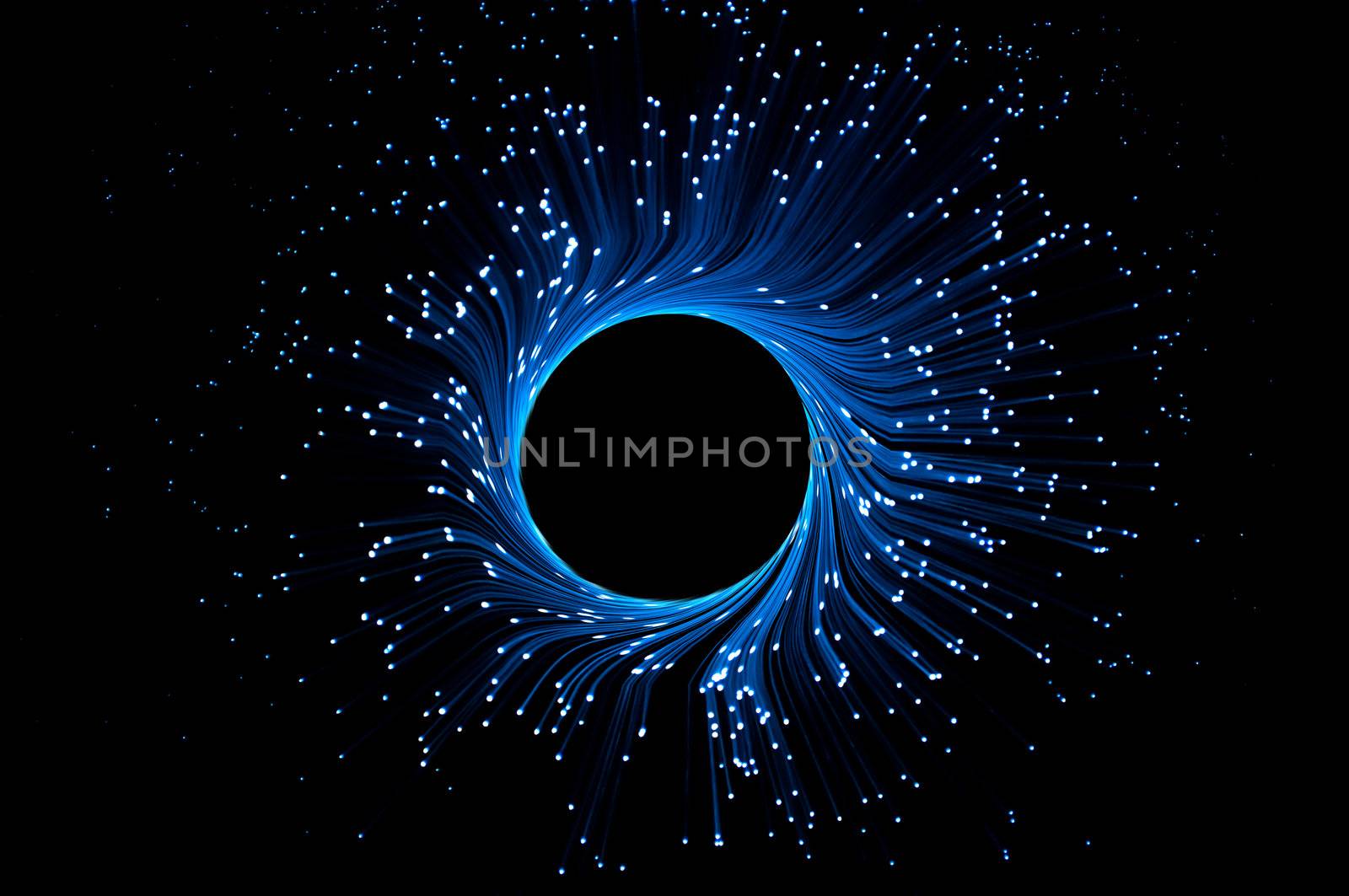 Illuminated blue fiber optic light strands forming a ring against a black background