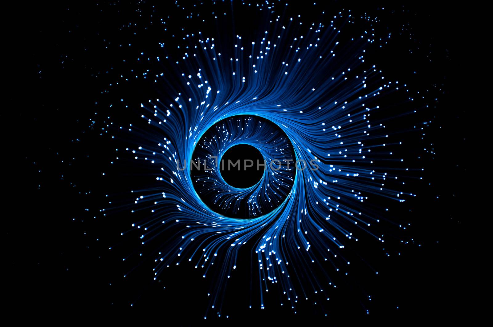 Illuminated blue fibre optic light strands forming swirling rings against a black background.