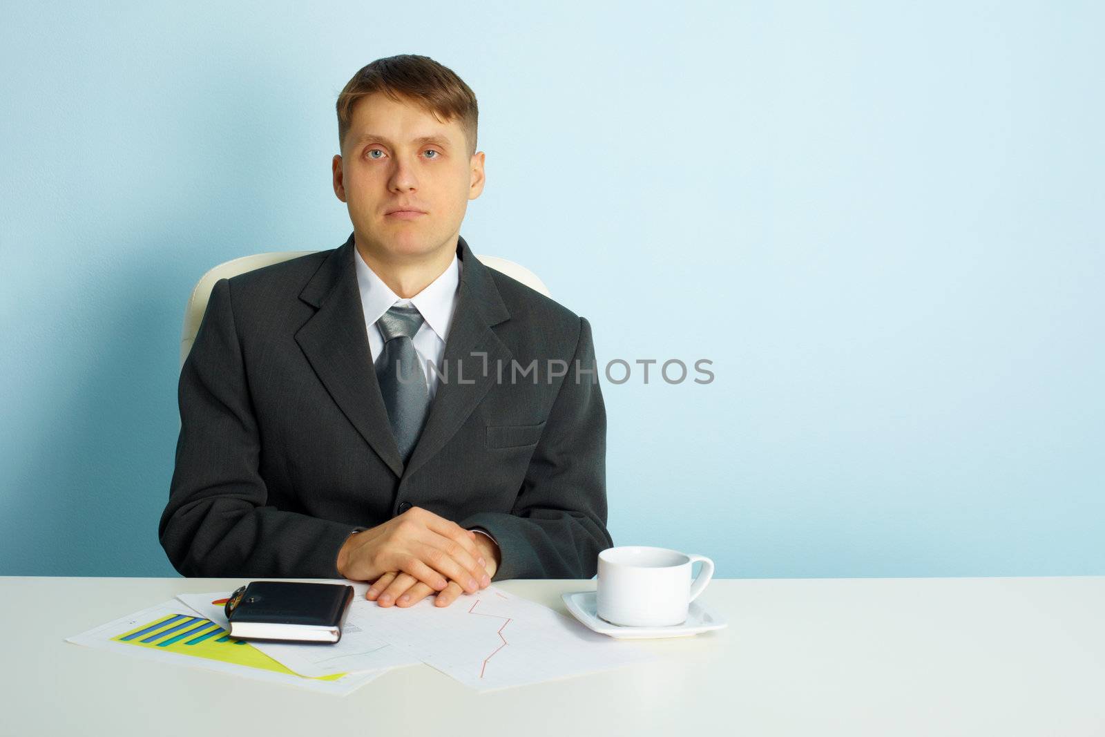 Quiet business young man sits at a desk in the office
