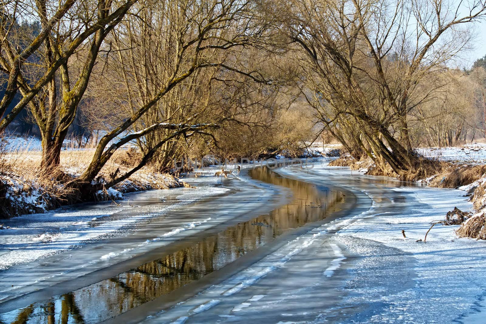 Sunny day in winter landscape with frozen river