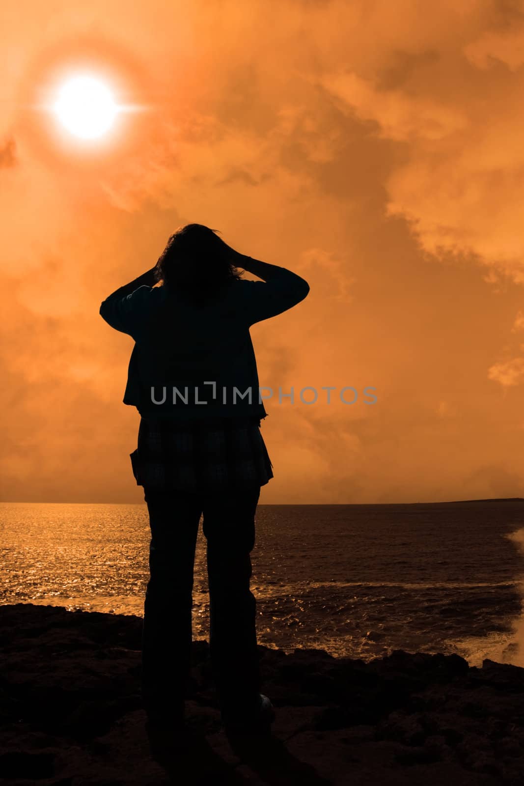 silhouette of a sad lone woman on a cliff edge by morrbyte