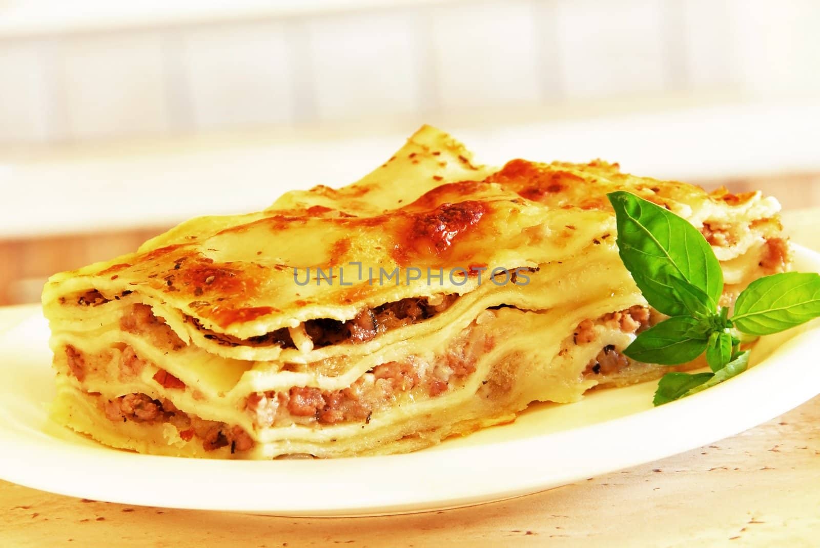 appetizing lasagna piece with basil on white plate