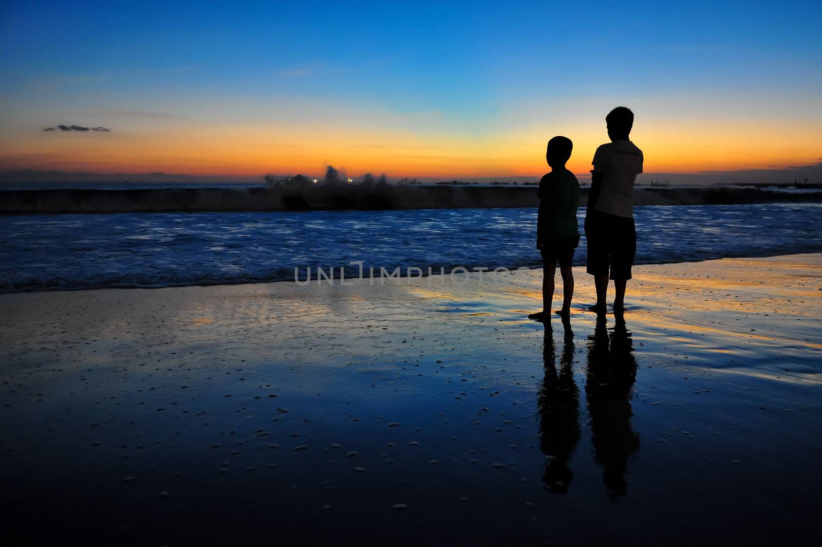 Two boys at ocean coast at sunset by martinm303