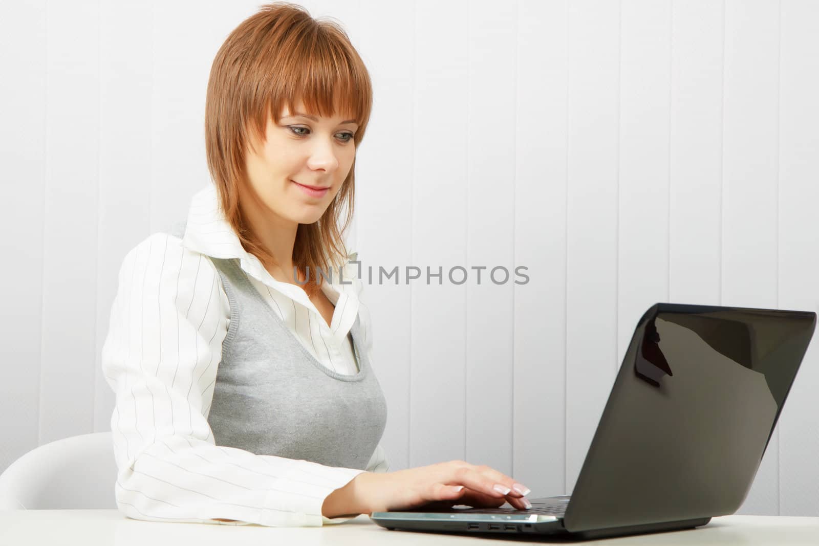 Attractive smiling happy girl with a laptop in the office