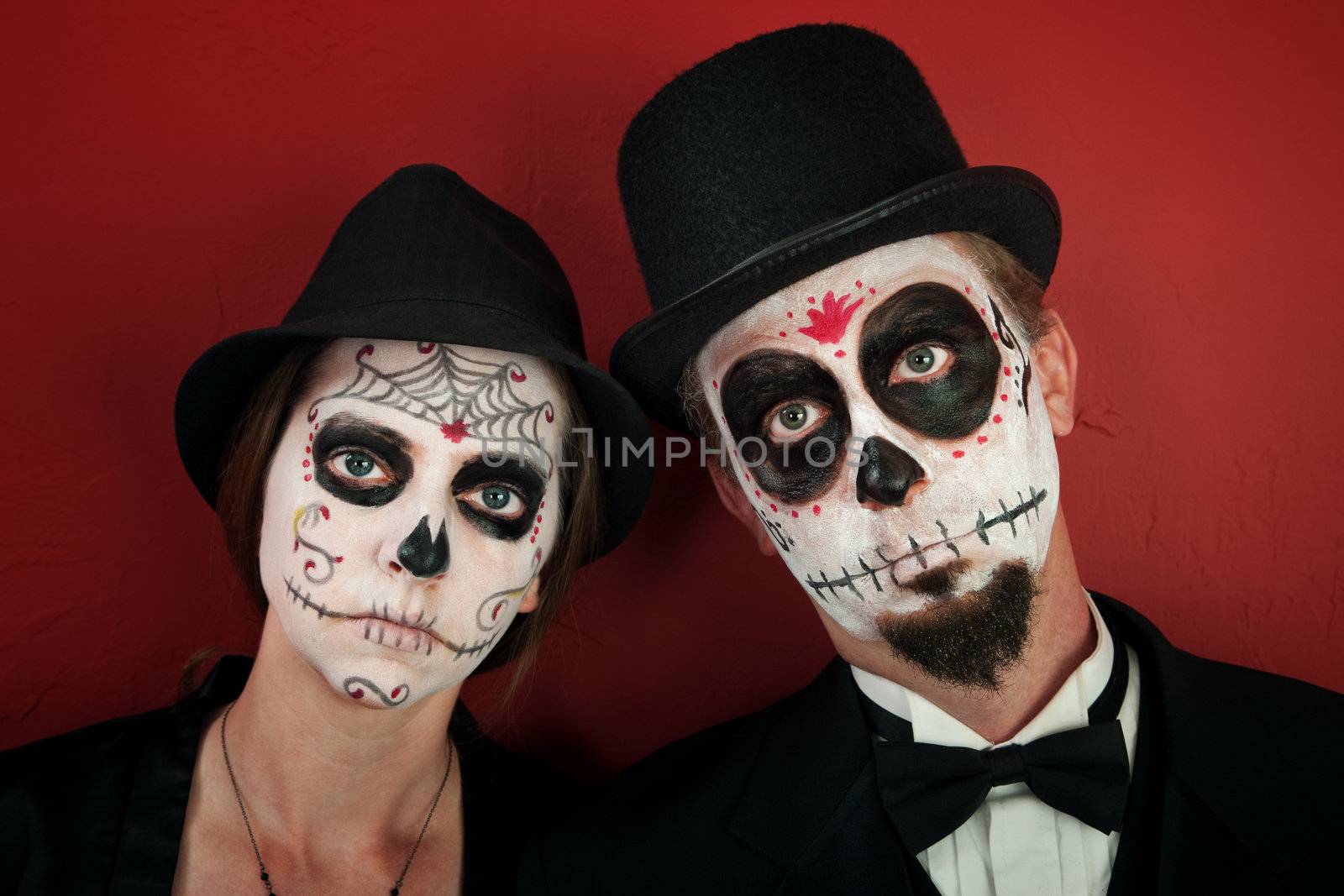 Serious couple in skull and cobweb makeup with hats