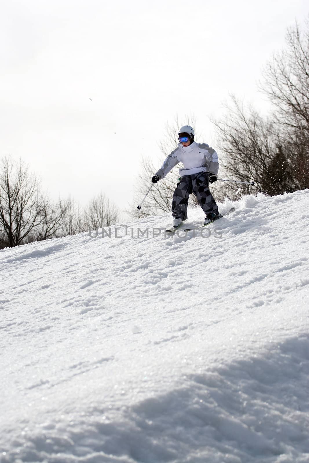 A youth freestyle skier skiing down the snowy mountain.