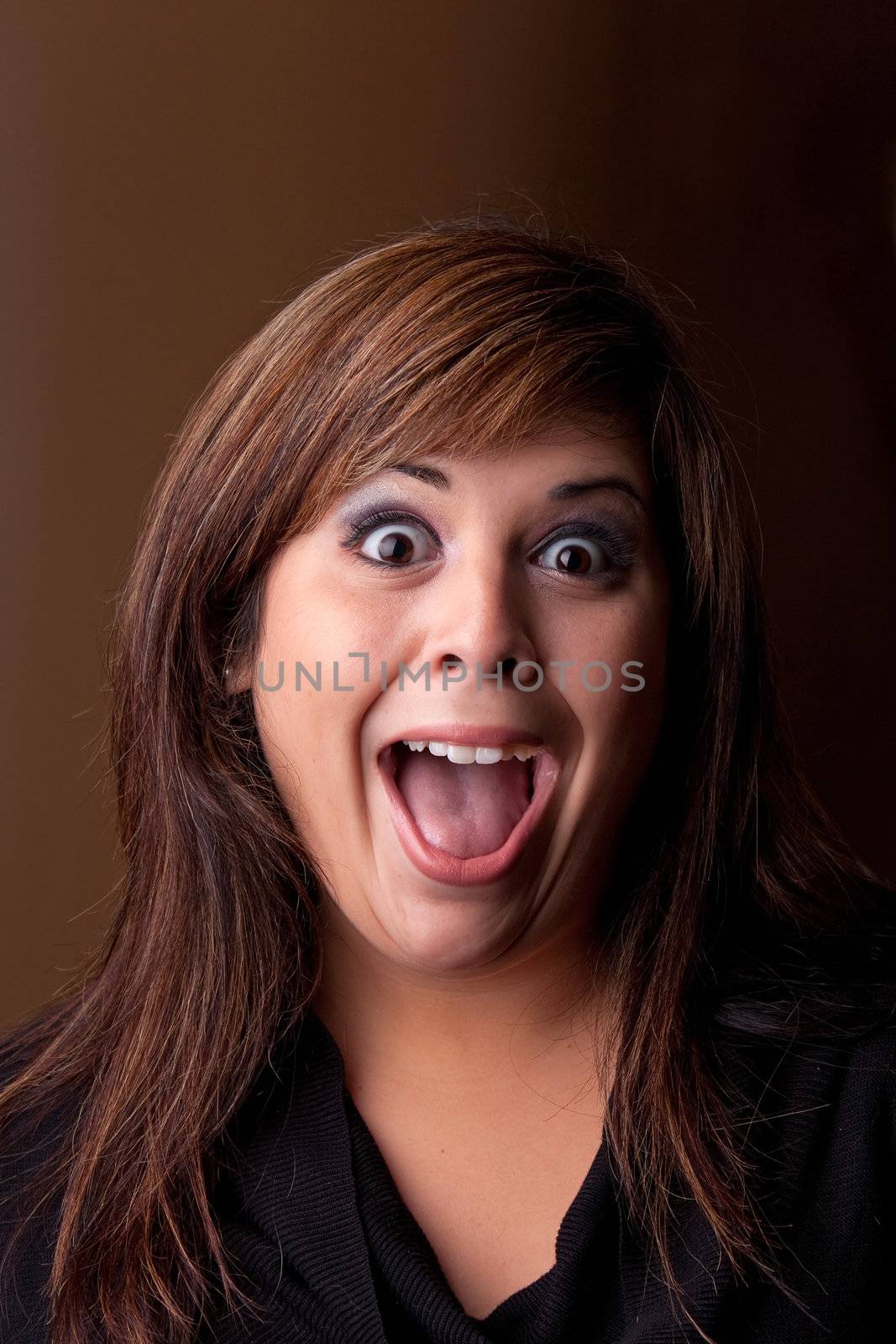 Woman with a funny look on her face smiles over a dark background.