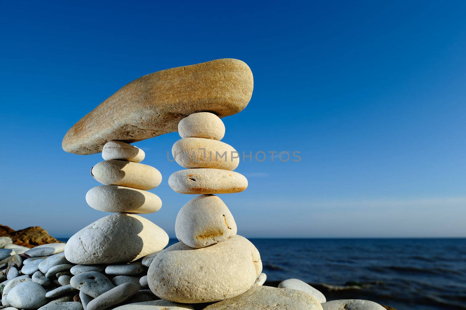 Long horizontal stone between a two stacks of pebbles