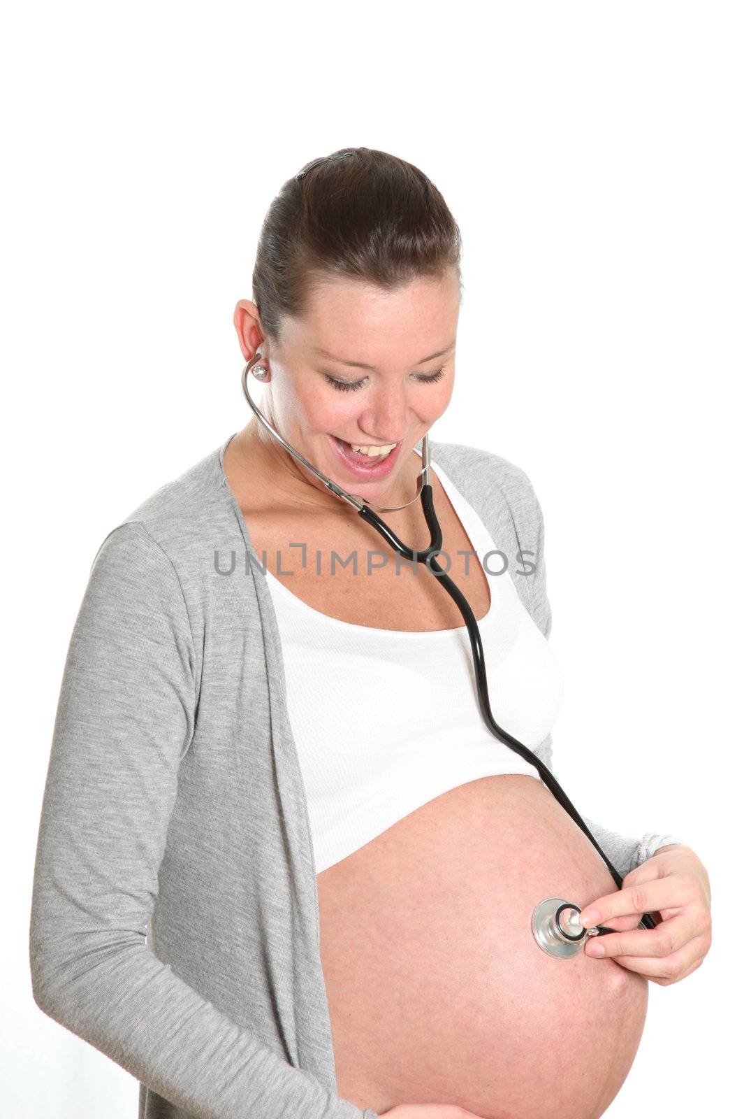 Happy, pregnant woman with stethoscope on belly hear your child and is looking forward
