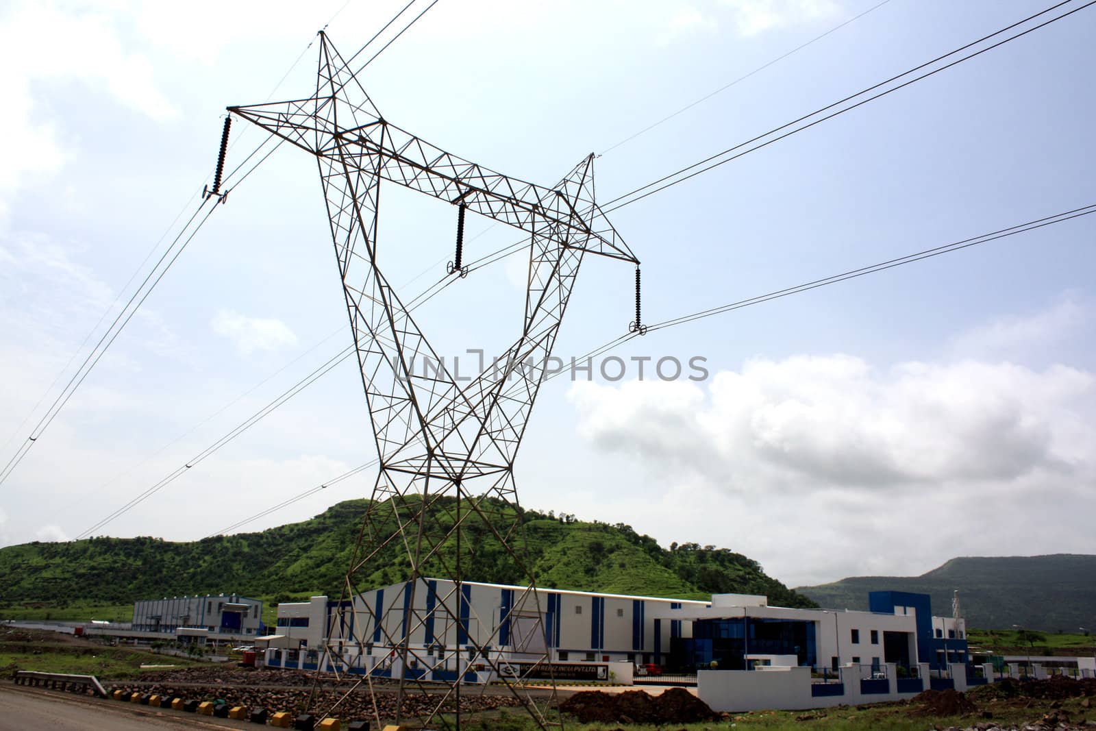 A tower of power cable lines leading to huge factories, in India.