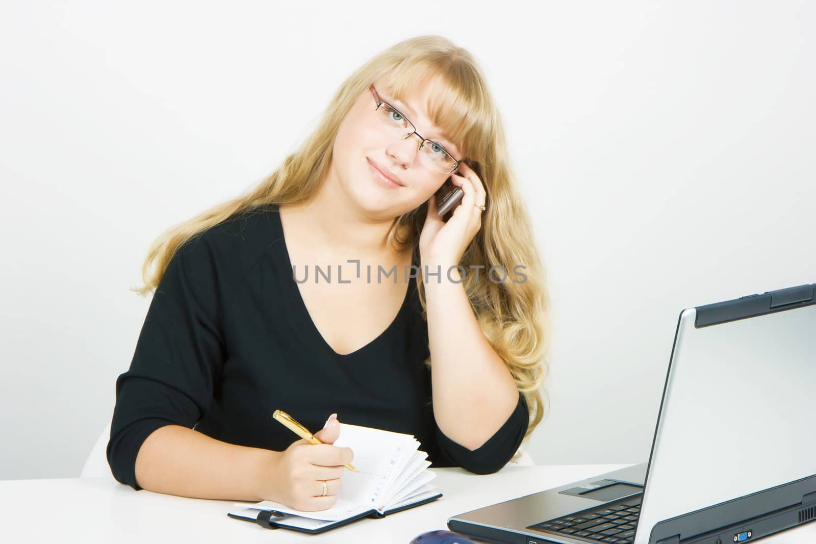 Blonde girl with laptop talking on a cell phone