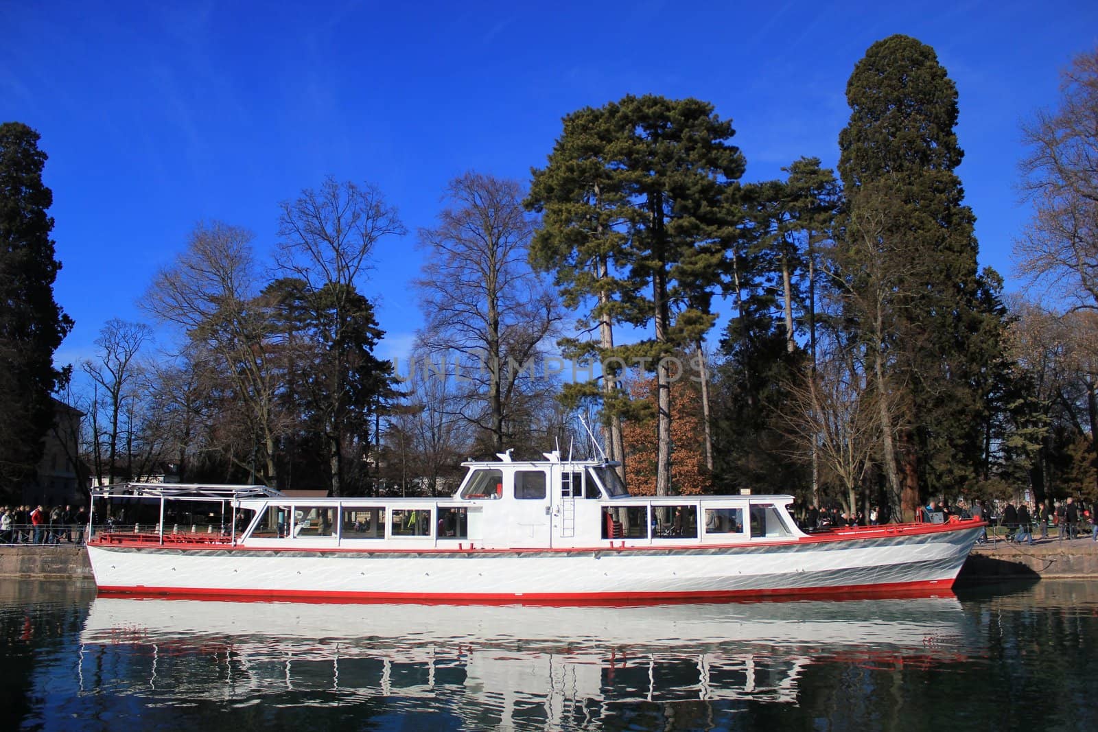 Red and white cruise boat on Annecy lake, France, by beautiful winter day