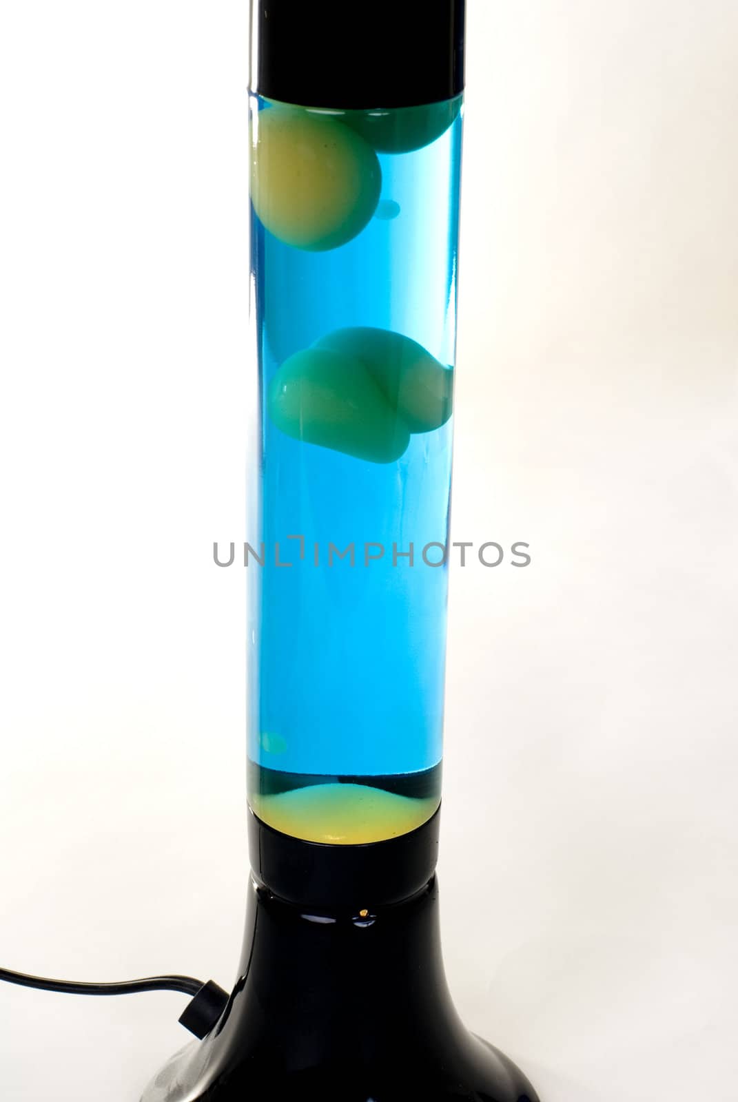 A Black lava lamp with blue liquid and green lava isolated on a white background. 