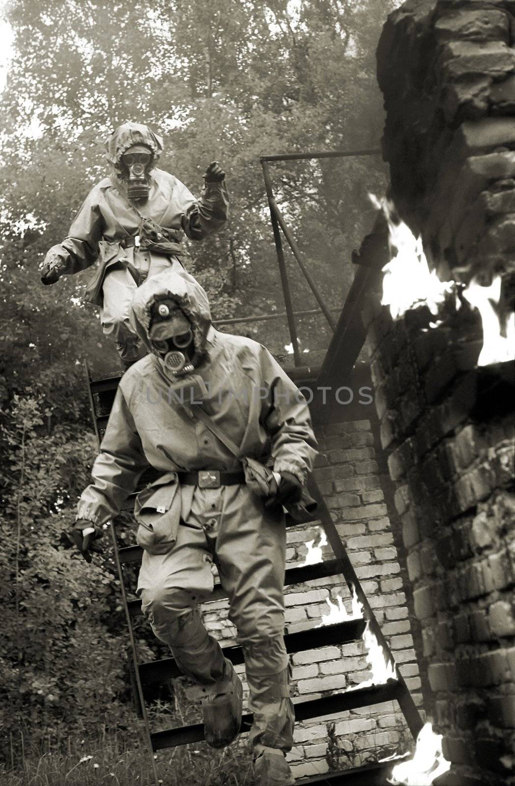 two men in gas-masks running downstairs with the fire near them