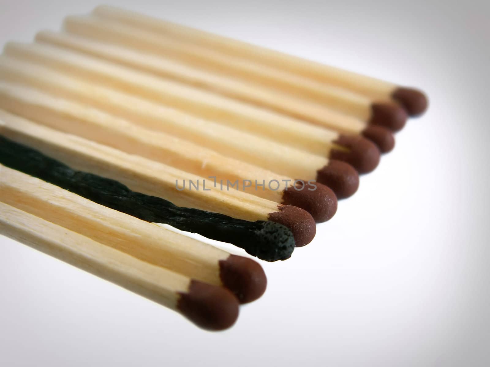 Close-up photo of several matches in a row with one burnt