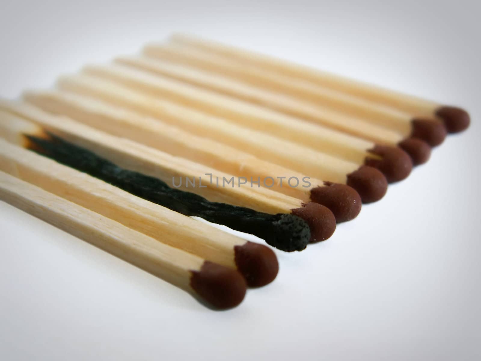 Close-up photo of several matches in a row with one burnt