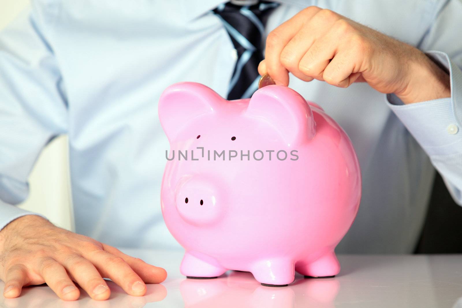young man with pink piggy bank and coin
