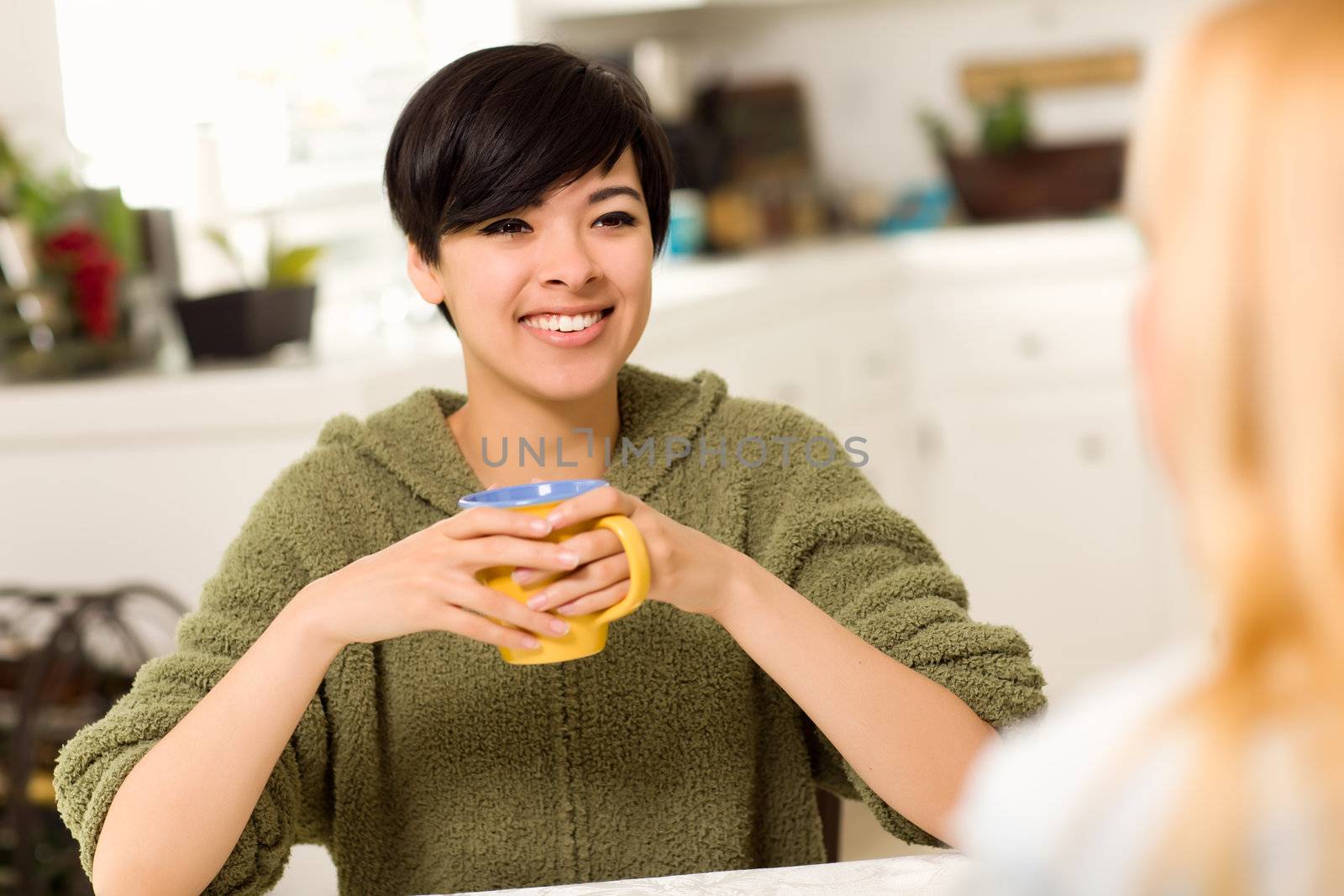 Multi-ethnic Young Attractive Woman Socializing with Friend in Her Kitchen.