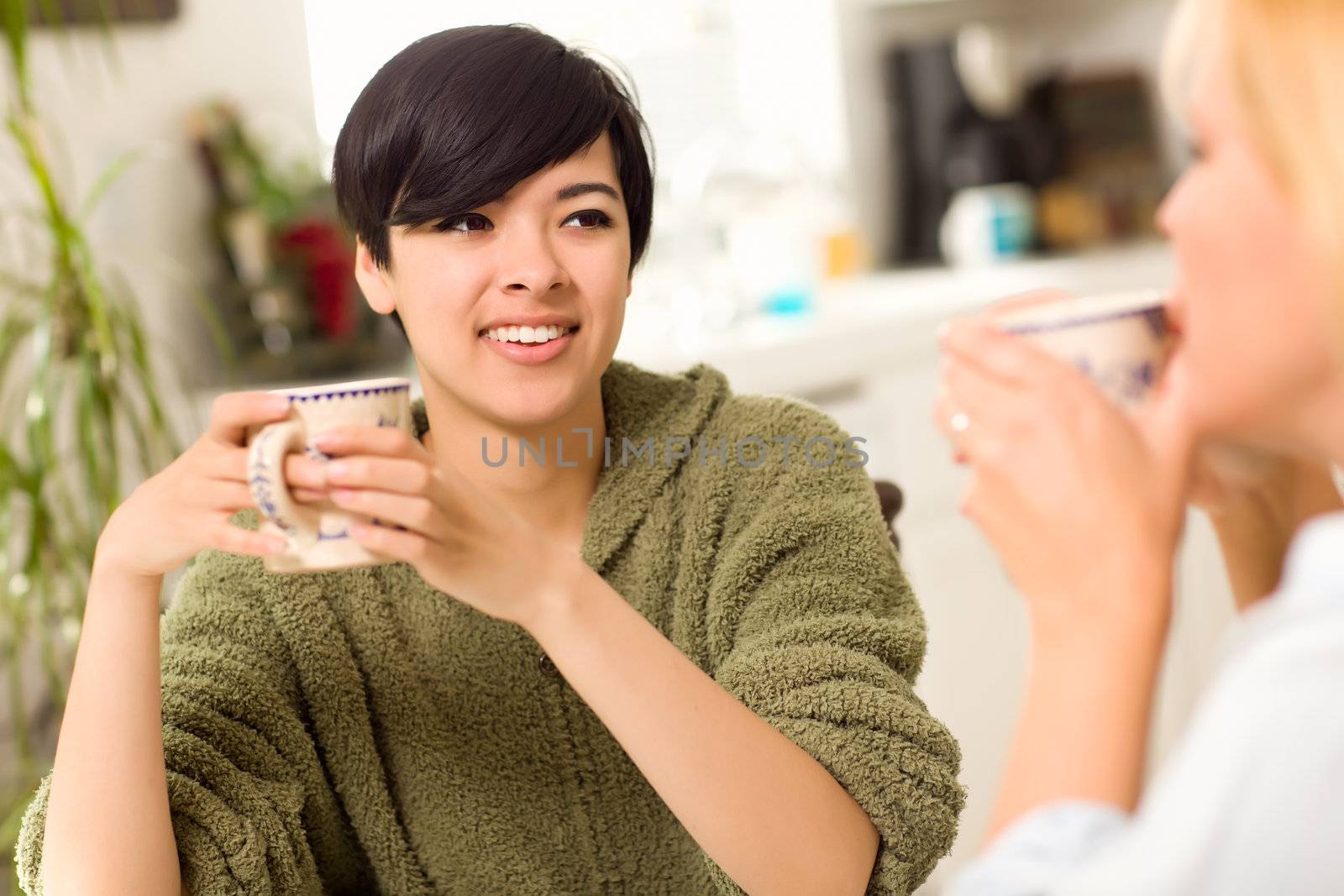 Multi-ethnic Young Attractive Woman Socializing with Friend in Her Kitchen.