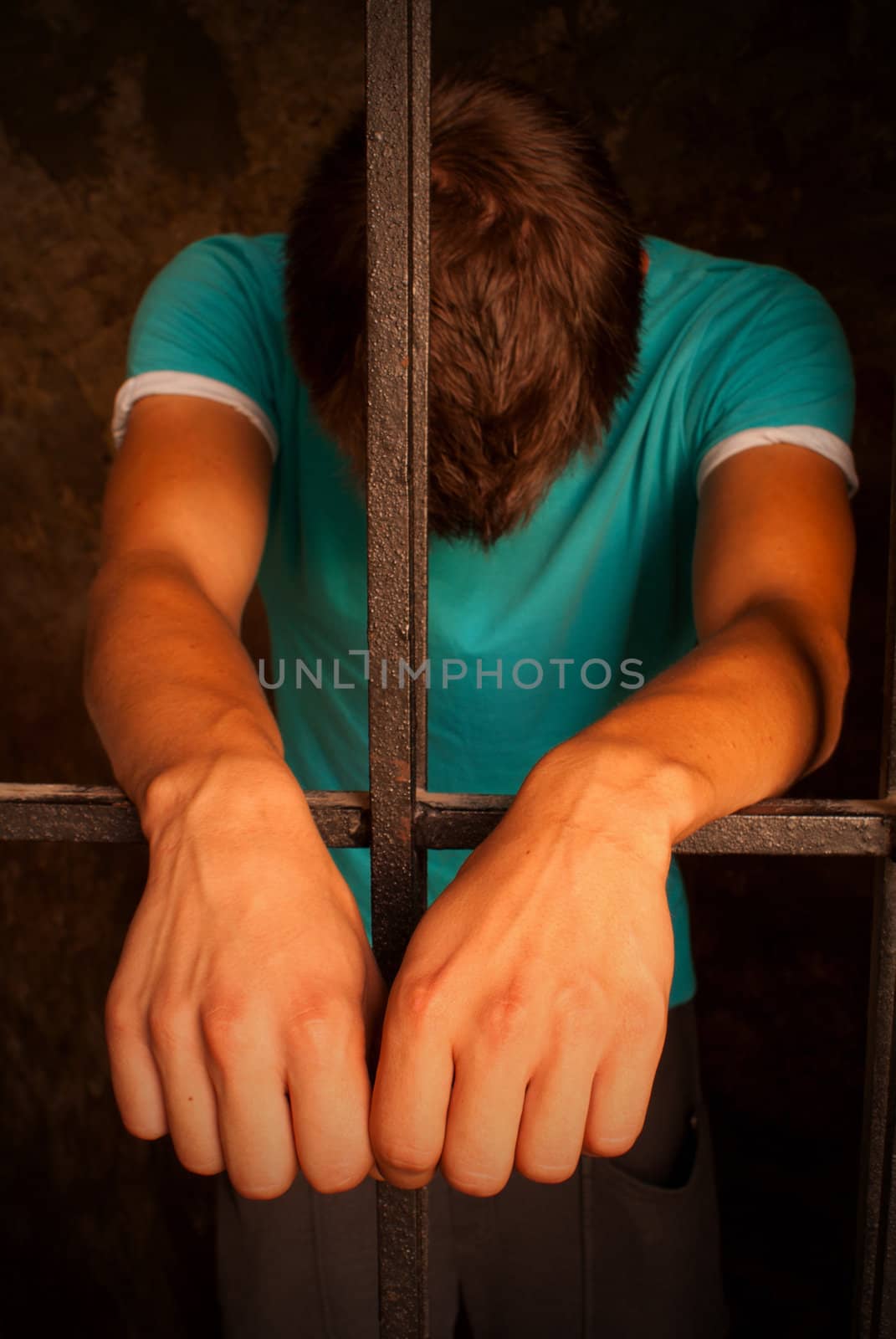 Man with hands tied with rope behind the bars