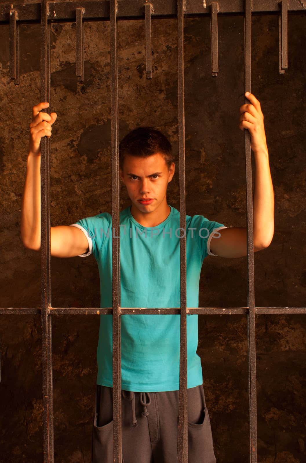 Man with hands tied with rope behind the bars by AndreyKr