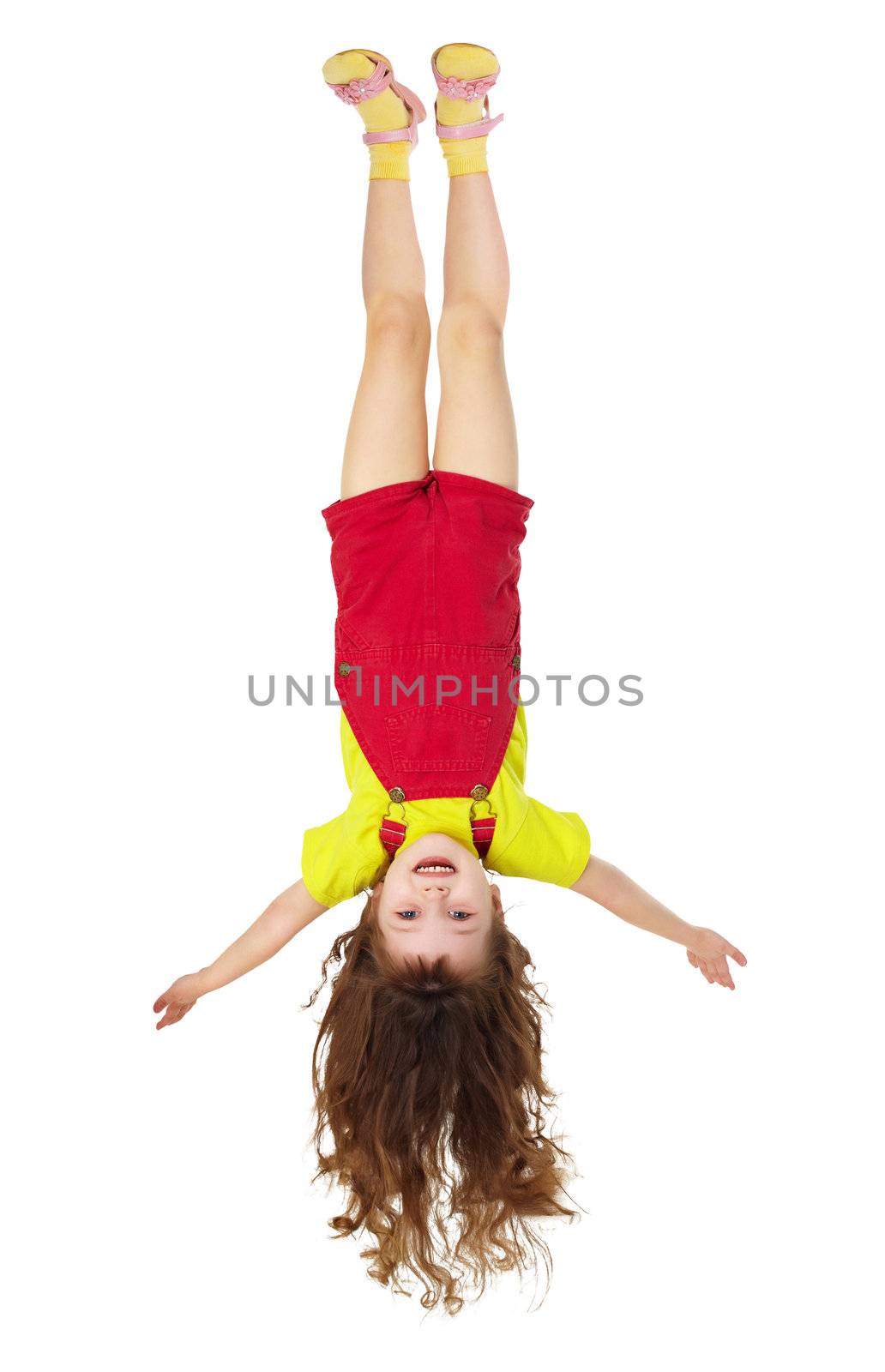 Cheerful little girl hangs upside down on white by pzaxe